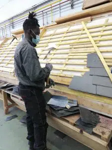 Photo d'un jeune apprentiti couvreur devant sont établit de travail